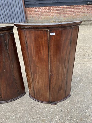 Lot 58 - Two George III mahogany bowfront corner cupboards