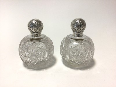 Lot 91 - A pair of Victorian silver mounted and cut glass scent bottles, of globular form, the tops relief-decorated