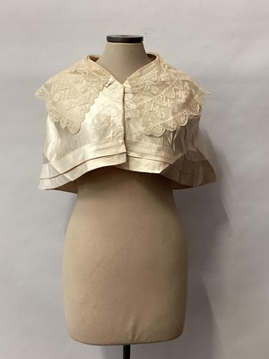 Lot 2117 - 1845 Victorian wedding dress in cream silk folded pleats on boned bodice with pointed waistline, two tier sleeves, detachable large bow to be worn at the waist, matching short cape silk cape trimme...