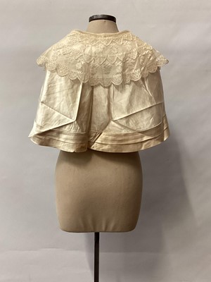 Lot 2117 - 1845 Victorian wedding dress in cream silk folded pleats on boned bodice with pointed waistline, two tier sleeves, detachable large bow to be worn at the waist, matching short cape silk cape trimme...