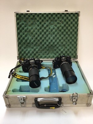 Lot 2371 - Two Nikon EM 35mm SLR cameras with telephoto lenses, in hard carry case