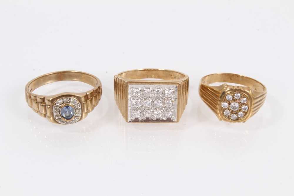 Lot 906 - Two 9ct gold rings set with synthetic white stones and one other 9ct gold blue stone ring, all with textured shoulders on 9ct yellow gold shanks (3)