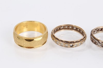 Lot 989 - Two 9ct gold gem set eternity rings, one other similar 9ct gold and silver ring and a Japanese yellow metal wedding ring
