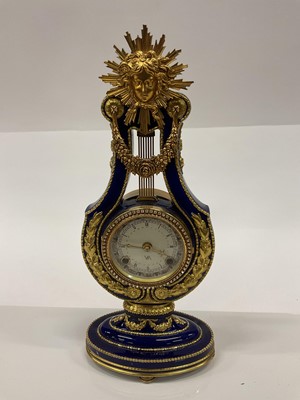 Lot 2616 - Marie-Antionette Clock by The Victoria & Albert Museum, in porcelain lyre shape case with gilt metal mounts and paste stones to the bezel. 39cm high.