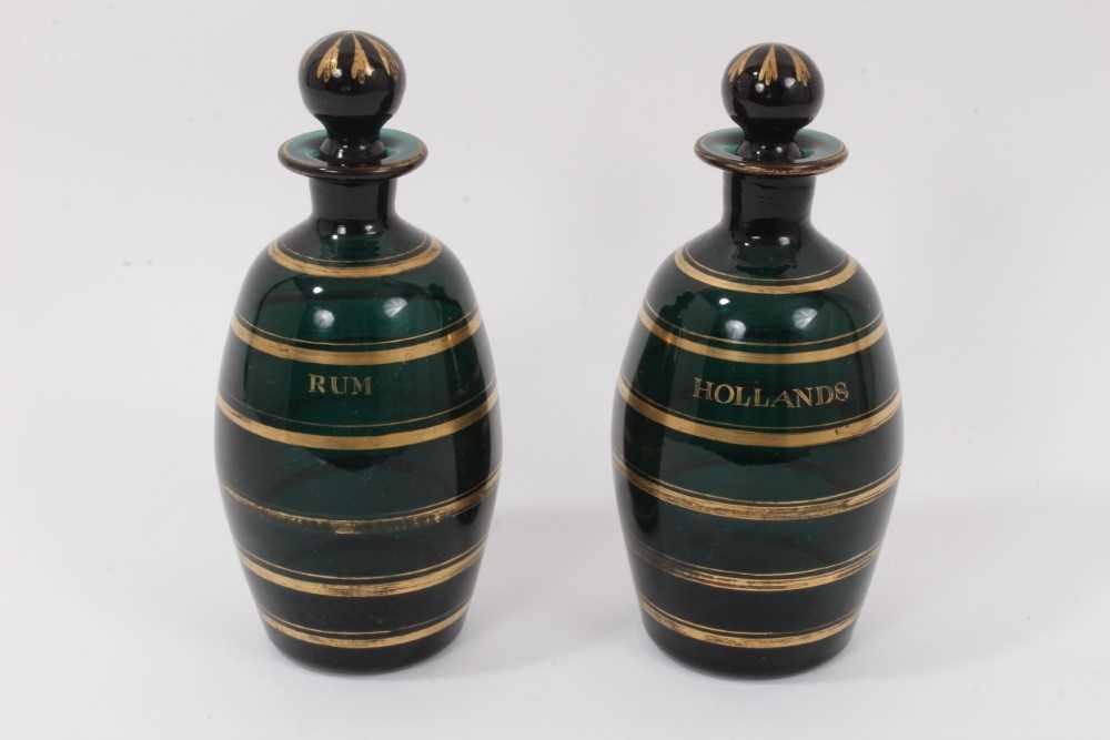 Lot 29 - A pair of early 19th century Bristol green glass ovoid-shaped decanters, decorated in gilt and labelled 'Rum' and 'Hollands', 20.5cm high