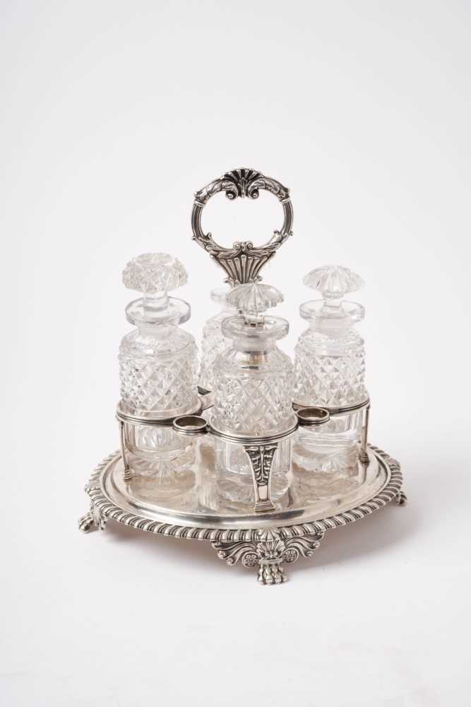 Lot 217 - Regency silver cruet of oval form with gadrooned border and four cut glass bottles, acanthus moulded handle raised on four lions paw feet, London 1821