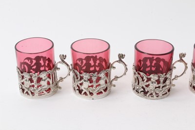 Lot 225 - Set six Edwardian silver mounted ruby glass beakers with rococo and cherub decoration, (Chester 1906), 6cm high
