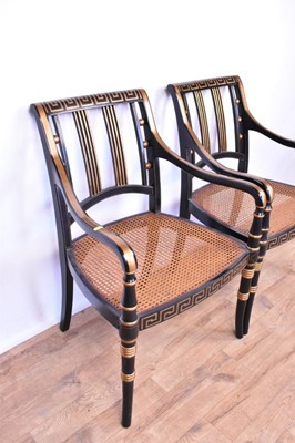 Lot 1359 - Pair of Regency style ebonised and gilt heightened open armchairs, each with Greek key top and seat rails, caned seat on splayed ring turned legs