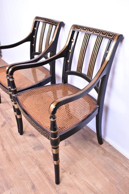 Lot 1359 - Pair of Regency style ebonised and gilt heightened open armchairs, each with Greek key top and seat rails, caned seat on splayed ring turned legs