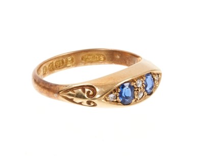 Lot 402 - Edwardian sapphire and diamond ring with two oval mixed cut blue sapphires interspaced by rose cut diamonds in boat-shape gold setting with carved gold shoulders, Chester 1906. Ring size M½.
