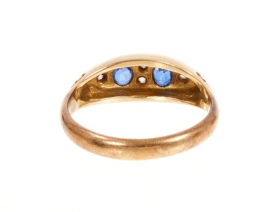Lot 402 - Edwardian sapphire and diamond ring with two oval mixed cut blue sapphires interspaced by rose cut diamonds in boat-shape gold setting with carved gold shoulders, Chester 1906. Ring size M½.