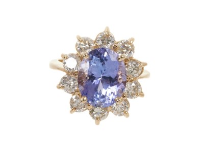 Lot 438 - Tanzanite and diamond cluster ring with an oval mixed cut tanzanite measuring approximately 10.8mm x 8.8mm x 6.2mm surrounded by a border of ten brilliant cut diamonds in gold claw setting on 14ct...