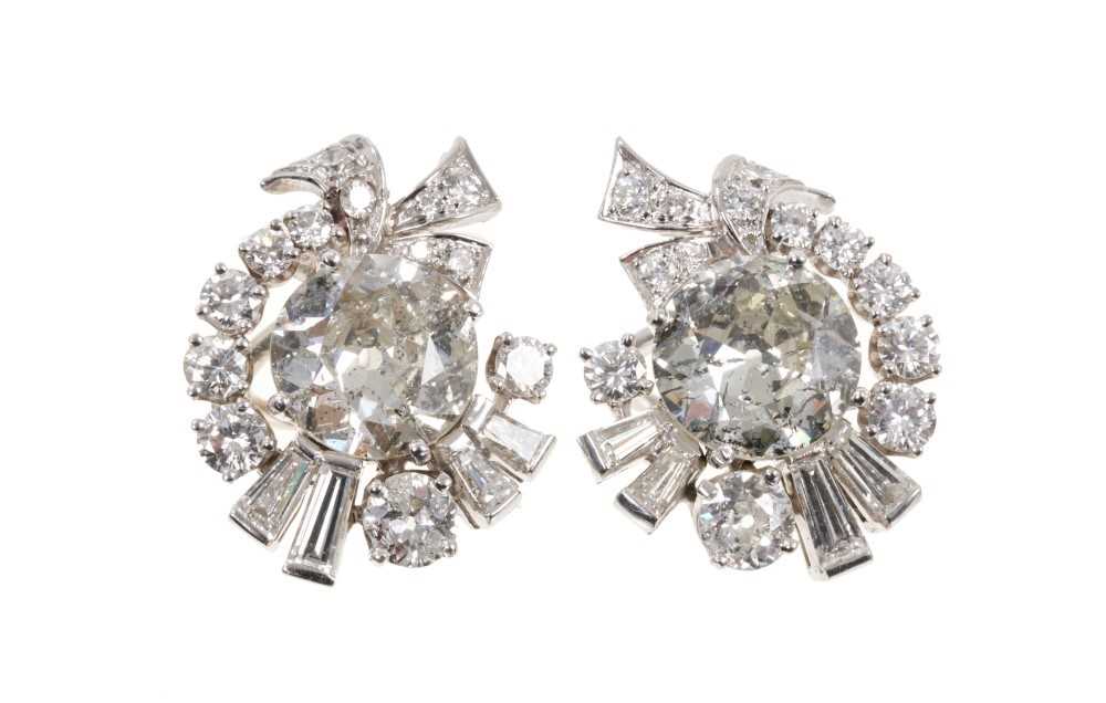 Lot 419 - Pair of 1950s diamond earrings, each with a central large old cut diamond surrounded by a scroll design of graduated old cut, brilliant cut and tapered baguette cut diamonds. The two principal diam...
