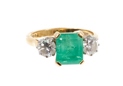 Lot 484 - Emerald and diamond three stone ring with a rectangular step cut emerald measuring approximately 8.3mm x 7mm x 5.8mm, flanked by two brilliant cut diamonds in claw setting on 18ct yellow gold shank...