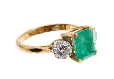 Lot 484 - Emerald and diamond three stone ring with a rectangular step cut emerald measuring approximately 8.3mm x 7mm x 5.8mm, flanked by two brilliant cut diamonds in claw setting on 18ct yellow gold shank...