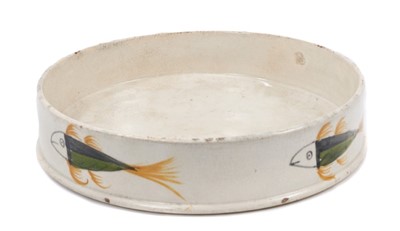 Lot 129 - An early 19th century pearlware pottery char dish, naively painted with fish in ochre, green and black, 17cm diameter