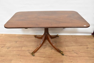Lot 1451 - Regency mahogany breakfast table, rounded rectangular tilt top with reeded edge on turned column and splayed quadruped reeded supports on brass capping and castors, 144 x 81cm