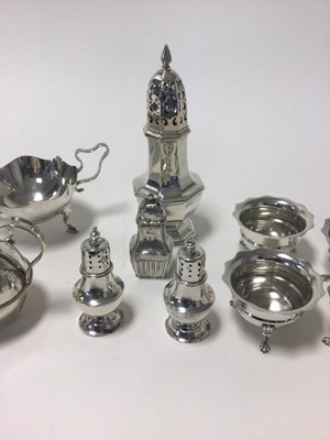 Lot 22 - Set of four George V silver salts, with shaped rims, central band, and shell feet, Birmingham 1919, 3.2 oz, together with a plated sugar bowl and jug with shaped rim and handles and hoof feet, and...