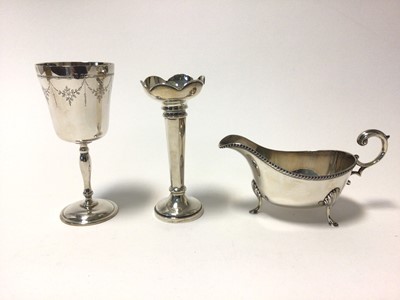 Lot 74 - A silver goblet with engraved swags, 14cm high, a weighted silver spill vase, and a George V silver sauceboat with scroll handles, reeded rim and hoof and shell feet, total weight 10.9oz