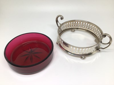 Lot 135 - Edwardian cranberry cut glass dish contained in a silver holder with scroll handles, four bun feet and pierced decoration, 10cm diameter excluding handles, Sheffield 1908 (Watson & Gillott)