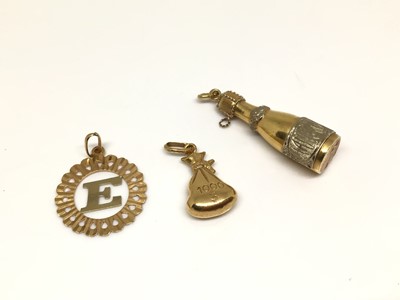 Lot 163 - Three 18ct gold pendants to include a champagne bottle, a money bag and an 'E' inital