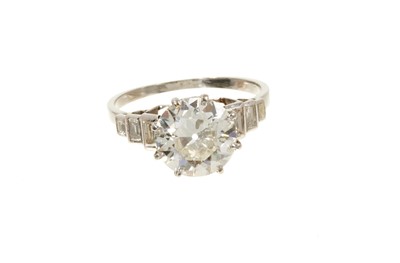 Lot 632 - Art Deco diamond single stone ring with a round old European cut diamond estimated to weigh approximately 2.5cts in eight claw setting flanked by six baguette cut diamonds to the stepped shoulders...
