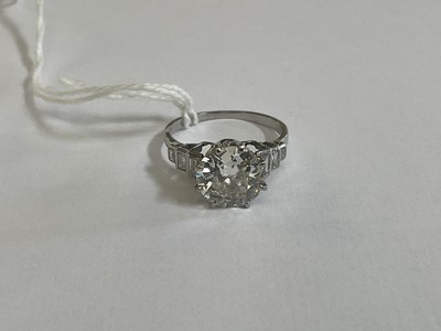 Lot 632 - Art Deco diamond single stone ring with a round old European cut diamond estimated to weigh approximately 2.5cts in eight claw setting flanked by six baguette cut diamonds to the stepped shoulders...