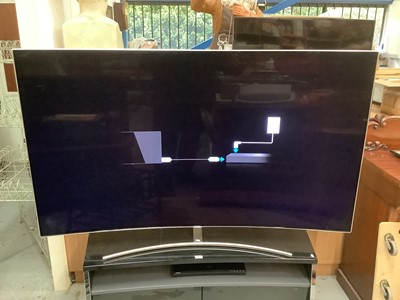 Lot 1 - 75" Qled Curved Samsung TV together with Stand and remote control. Television currently turns on but not working as it's missing it's Fibre optic lead.