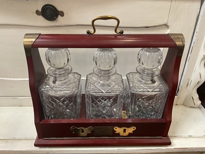 Lot 360 - Edwardian style three bottle tantalus with three cut glass decanters in mahogany frame