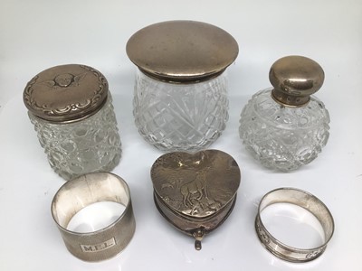 Lot 1132 - Silver heart shaped jewellery box with stag decoartion, three silver topped cut glass vanity jars and two silver napkin rings