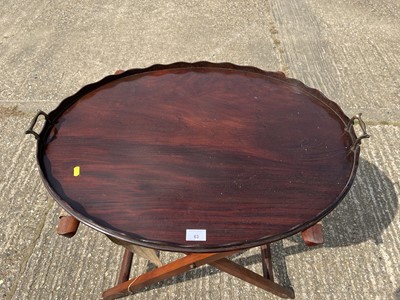Lot 63 - Edwardian oval mahogany two handled tray with shaped edge, on associated folding stand, tray 77cm x 57cm