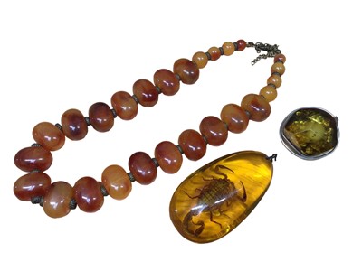 Lot 112 - Large reconstituted amber pendant with a scorpion inside, reconstituted amber brooch in white metal mount and a plastic bead necklace