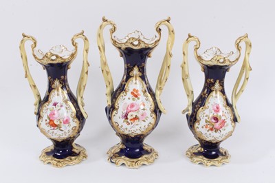 Lot 345 - Garniture of three Regency vases, each of slender baluster form with scrollwork moulding and branch-form handles, decorated with panels of flowers on a gilt-patterned, cobalt blue and pale yellow g...