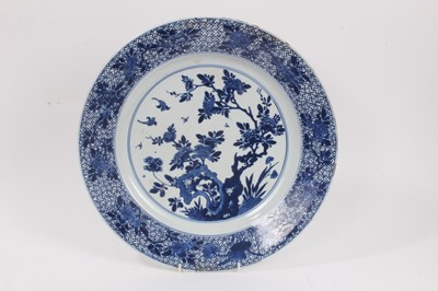 Lot 349 - Chinese blue and white porcelain dish, early 18th century, decorated with two birds amongst foliage, the border with flowers on a geometric-patterned ground, double ring mark to base, 34cm diameter