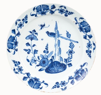 Lot 350 - 18th century blue and white Delftware dish, decorated in the Chinese style with a bird perched amongst rockery, the border with flowers, 33.5cm diameter