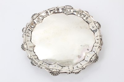 Lot 550 - George III silver waiter of circular form, with scroll and shell border, on three hoof feet (