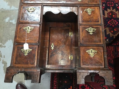 Lot 1055 - George II walnut and crossbanded and featherbanded kneehole desk, the top with re-entrant angles, having seven drawers and shaped frieze drawer about the cupboard kneehole on bracket feet, 69cm wid...