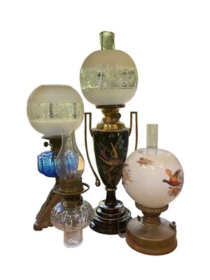 Lot 222 - Good quality Victorian oil lamp decorated with polychrome exotic bird on black glazed ceramic body, together with three other oil lamps (4)