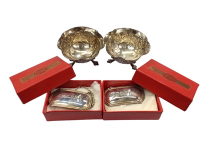 Lot 1084 - Pair of modern sterling silver wine labels and a pair of silver salts with relief decoration on paw feet (4)