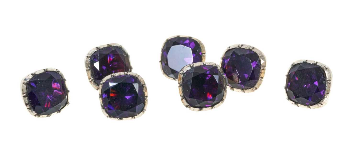 Lot 369 - Seven Georgian foil-backed silver and amethyst paste buttons with collet setting, circa 1800.