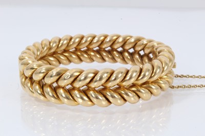 Lot 331 - Victorian yellow metal hinged bangle with a double rope twist design, stamped '18ct' to the clasp.