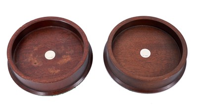 Lot 668 - Pair of contemporary mahogany wine bottle coasters with inset silver discs to the centres (London 1986).