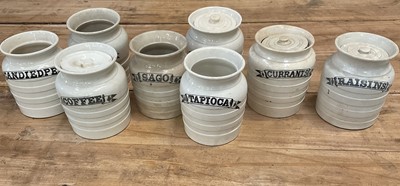 Lot 1411 - Group of eight late 19th/early 20th century white banded pottery kitchen storage jars, with titles printed in black in ribbons, including 'Coffee', 'Barley', 'Currants', etc, 15.5cm high