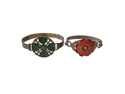Lot 9 - Chinese white metal bangle set with five carved green jade/ hard stone discs, together with a similar carnelian bangle (2)