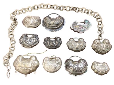 Lot 11 - Collection of eleven Chinese white metal padlock style pendants with floral scroll and character mark decoration. Largest measures 5.5cm wide, smallest 3.7cm wide