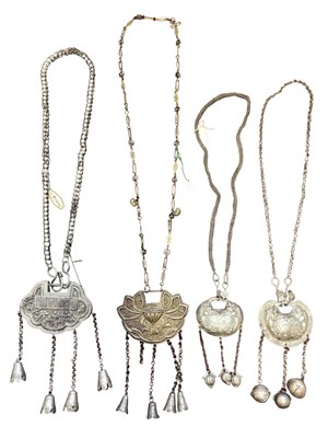 Lot 12 - Four old Chinese white metal necklaces with embossed panels depicting flowers, leaves, figures and Chinese characters, with bells suspended from chains