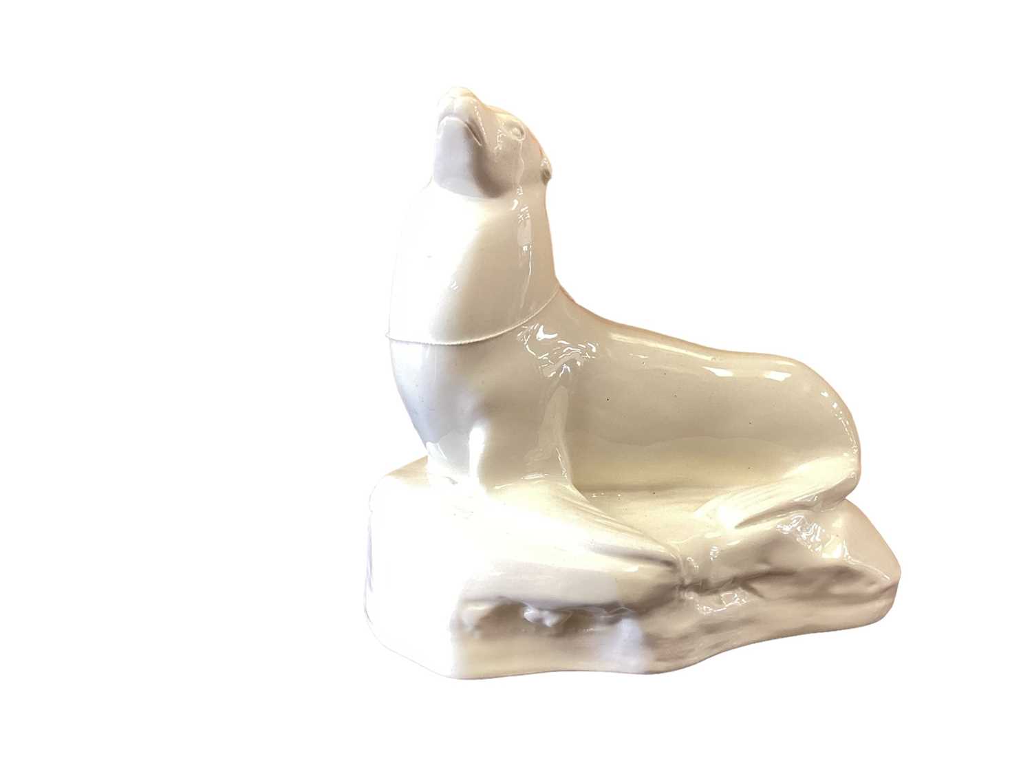 Lot 1203 - A John Skeaping for Wedgwood cream glazed model of a Seal, circa 1920s, the seal raised on front flippers and set on a stylised 'glacier' base, impressed 'John Skeaping' mark to back of base, impre...