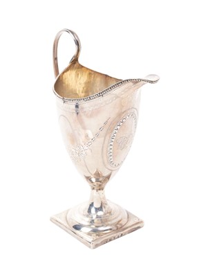 Lot 286 - George III silver cream jug of helmet form, with engraved decoration and initials, loop handle