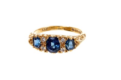 Lot 468 - Victorian style 18ct gold sapphire and diamond ring with three oval mixed cut blue sapphires and four brilliant cut diamonds in 18ct gold carved setting on tapered shank, London 1978. Ring size K.