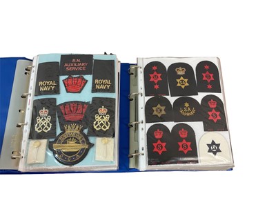 Lot 759 - Two albums of cloth Royal Navy badges and insignia to include cap tallies (2 albums)